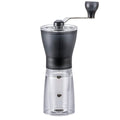 Hario Mini Slim+ manual coffee grinder with black handle and transparent grounds container