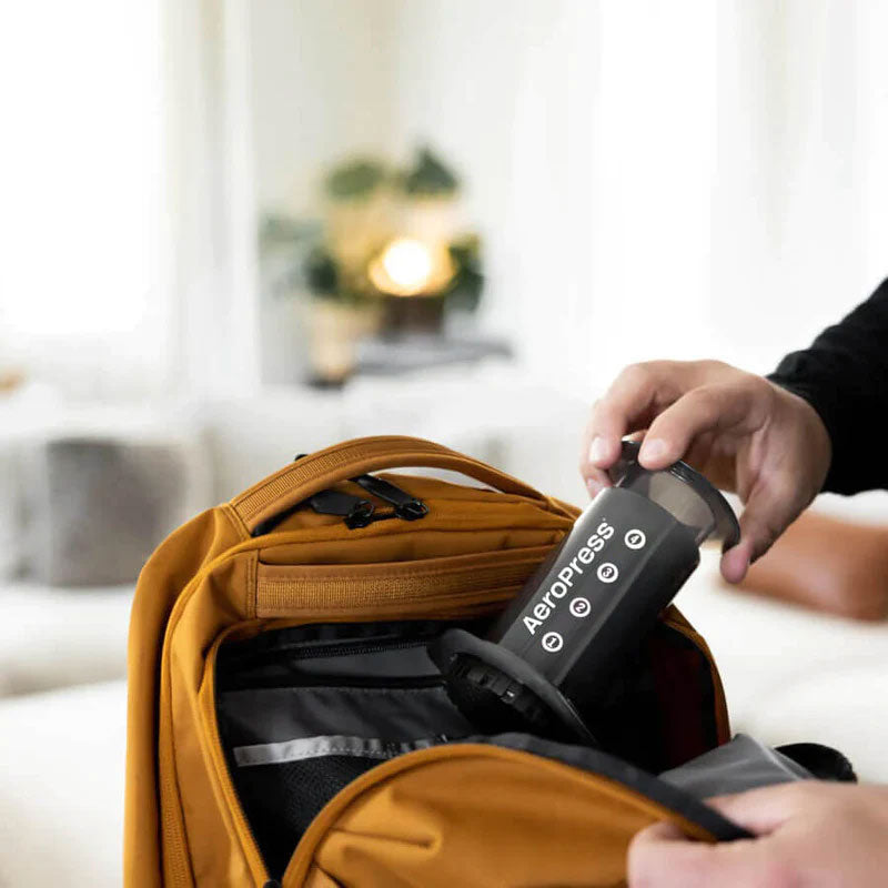 Hand packing an AeroPress Original into a backpack for travel; backpack not included.