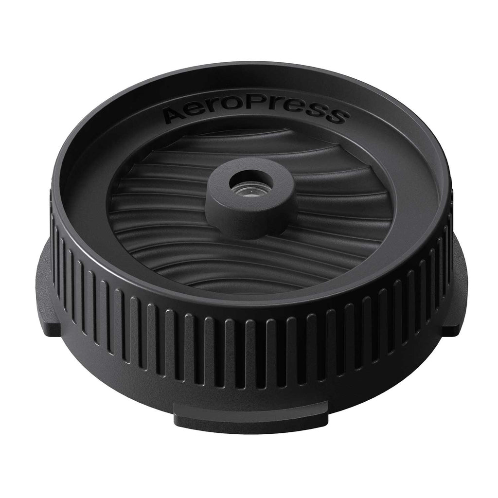 Angled view of the AeroPress Flow Control Filter Cap showing its ribbed body and wave-patterned top.