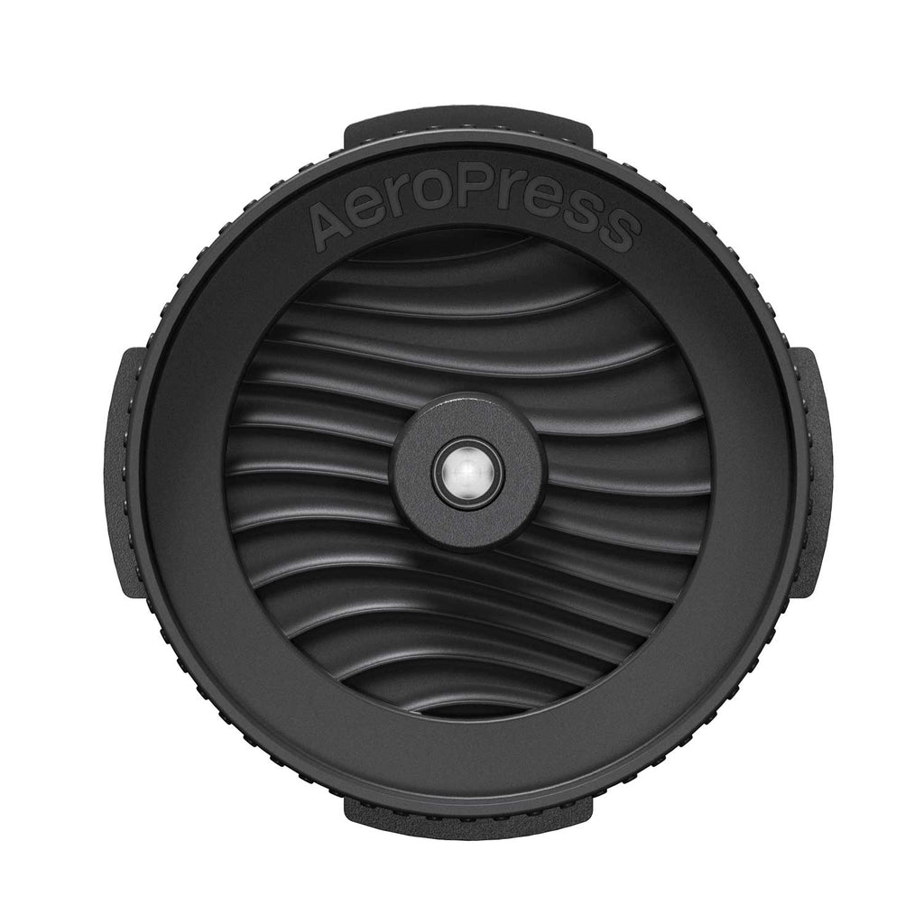 Top view of the AeroPress Flow Control Filter Cap showing its ridged rim and wave-patterned valve face.
