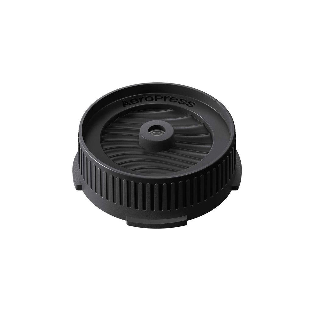 AeroPress Flow Control Filter Cap in black, shown at an angle on a white background.