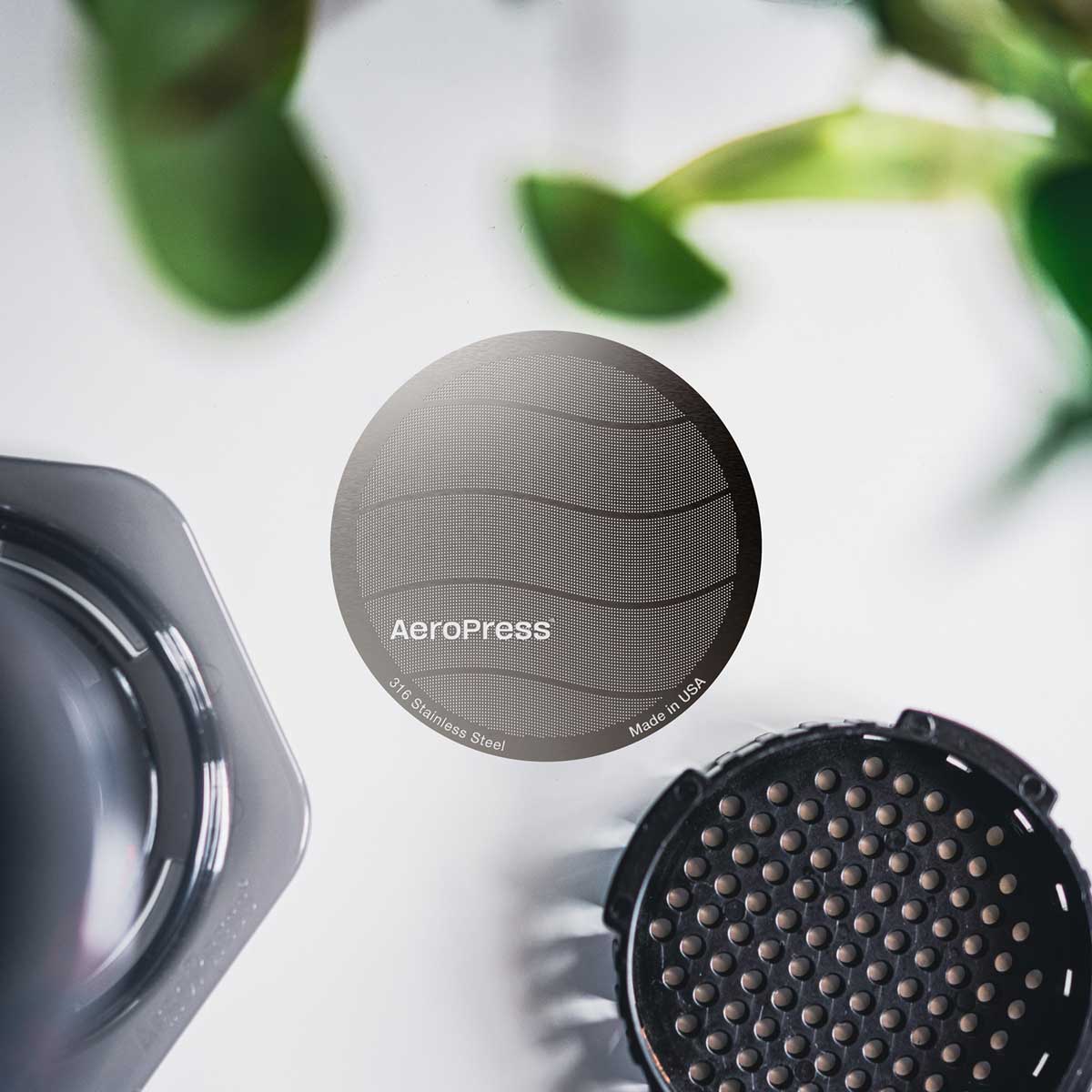 AeroPress standard stainless steel filter beside a brewer and filter cap, sold separately